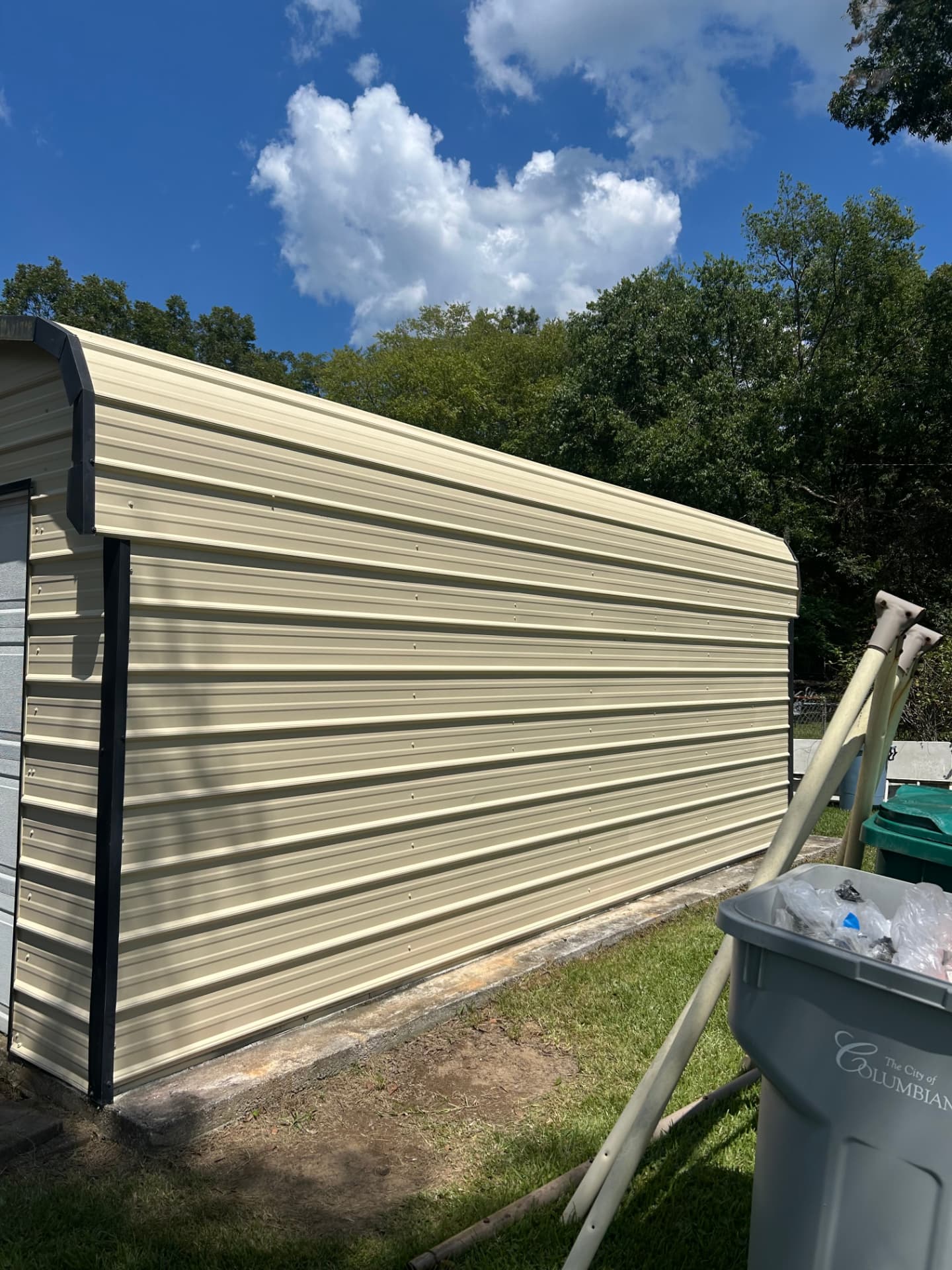 Long side of the finished metal outbuilding with painted corner trim on a raised slab