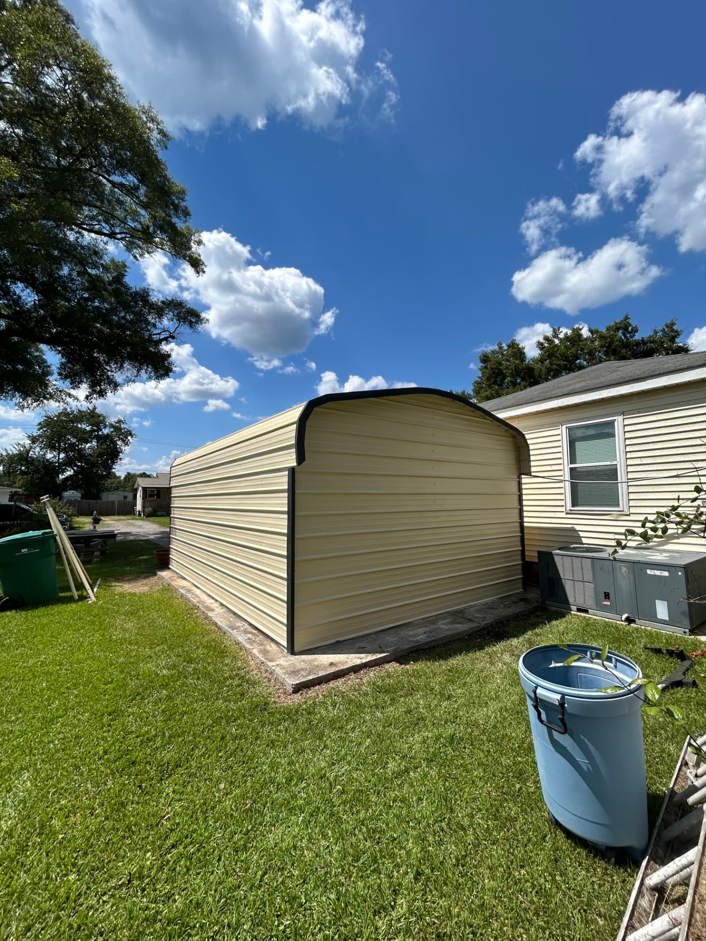 Rear view of the finished metal outbuilding set on the lawn beside the house